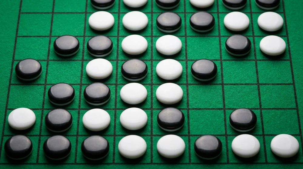 A dark disc being placed on a Reversi board to trap a line of light discs, shown for Reversi